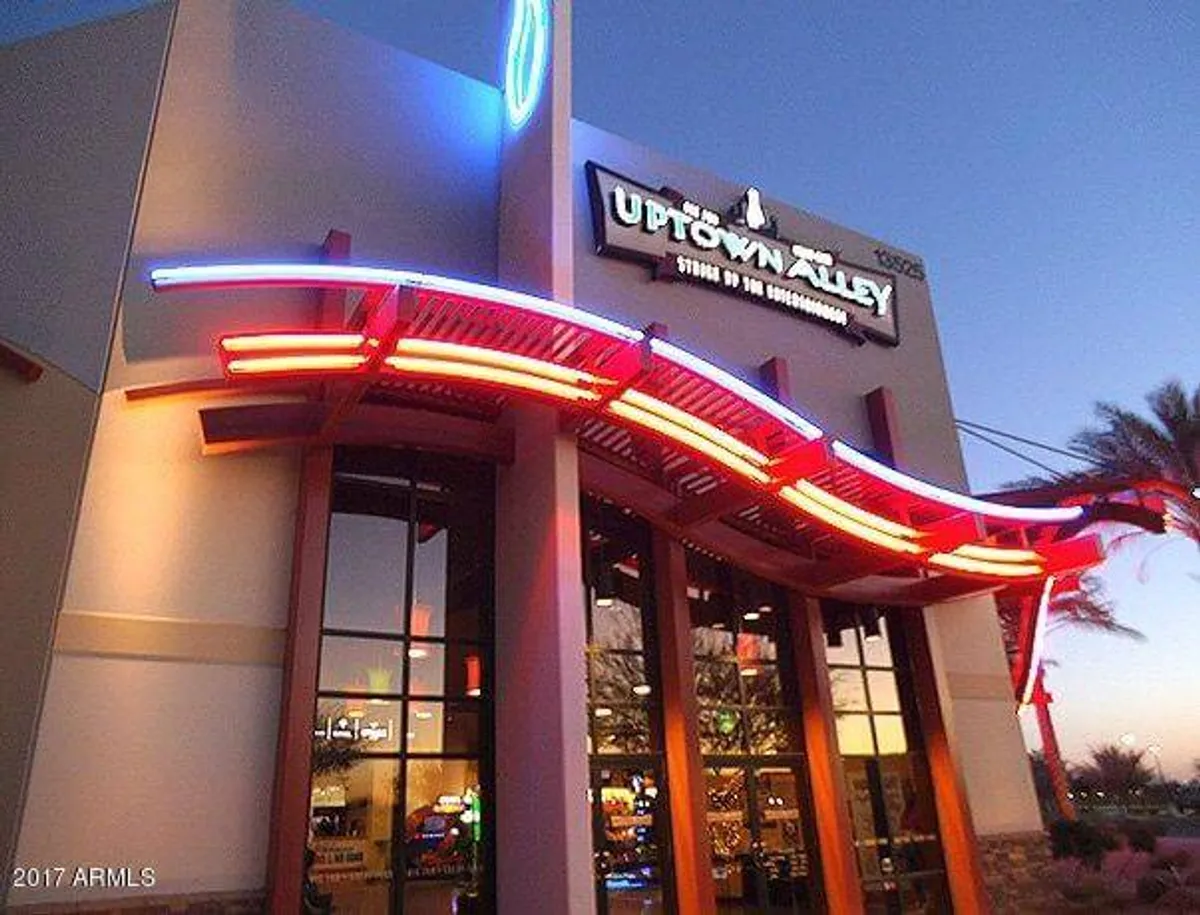 An exterior view of vibrant neon lighting and business signage, representing the energetic atmosphere of nightlife, dining, and entertainment options available in the area. Architectural elements hint at a lively local scene perfect for group outings.