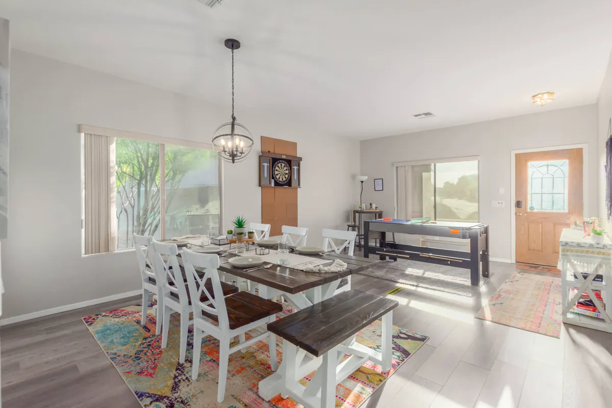 The image showcases a modern interior with a large dining table, a dartboard, and a welcoming entrance, creating an inviting space for group gatherings, meals, and late-night games.