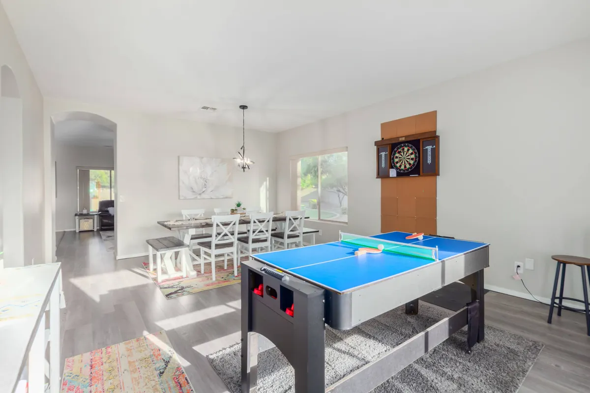 An interior game area featuring an air hockey table, dartboard, and dining table, set up for friendly competition and socializing.