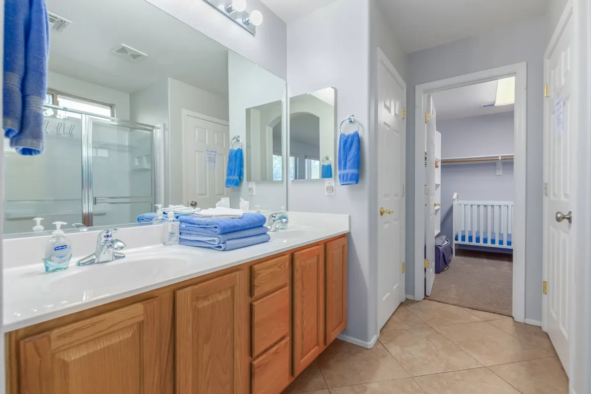 A calm, organized bathroom with a double sink vanity, mirrors, neatly folded towels, and a shower area. The room is well-lit, with a sense of order and relaxation, ideal for morning routines or evening unwinding.